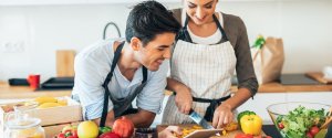 Male and female university students making a salad together in a shared student kitchen