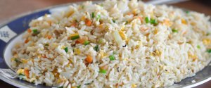 Homemade bowl of egg fried rice in a white bowl on a wooden surface