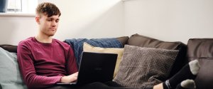 Student studying at home on a laptop on the sofa