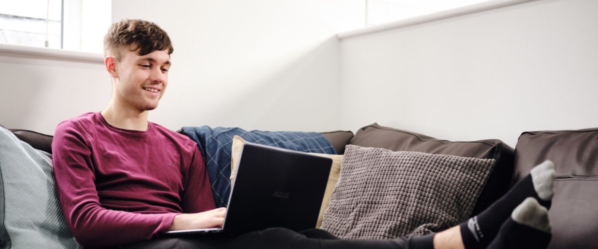 Student studying at home on a laptop on the sofa