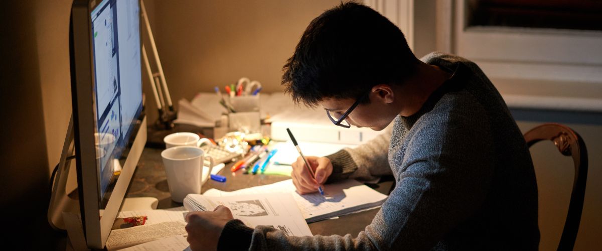 University student studying effectively at home at a desk by task lamp